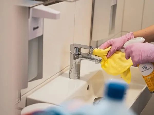 Reinigung eines Waschbeckens im Sanitärbereich mit Mikrofasertuch und Handschuhen